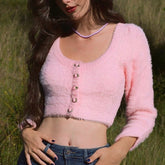 Woman wearing a pink fuzzy cardigan in a grassy field